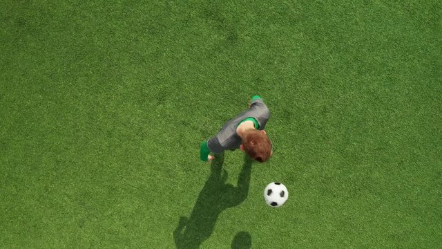 Top view from drone on football field football player stuffs ball. Soccer trains before match on football field on sunny day.