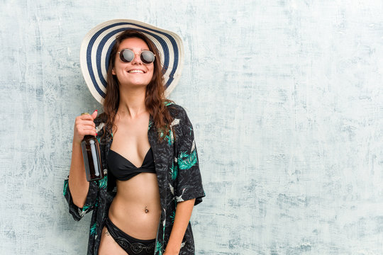 Young european woman wearing bikini and drinking a beer