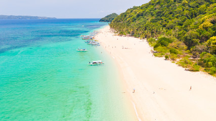 Puka Shell Beach, Boracay Island, Philippines, aerial view. Tropical white sand beach and beautiful lagoon. Tourist boats and people on the beach. People relax on the beautiful coast.