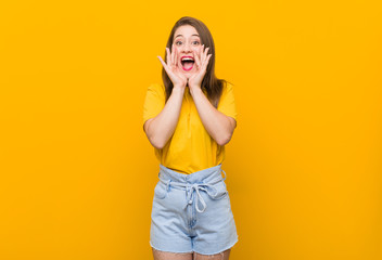 Young woman teenager wearing a yellow shirt shouting excited to front.