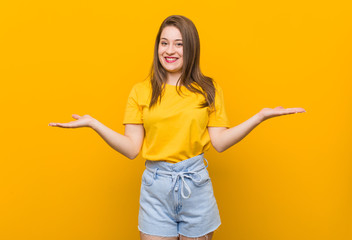 Young woman teenager wearing a yellow shirt showing a welcome expression.