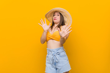 Young caucasian woman wearing a straw hat, summer look being shocked due to an imminent danger