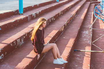 Young blonde girl in skirt sitting on painted stairs