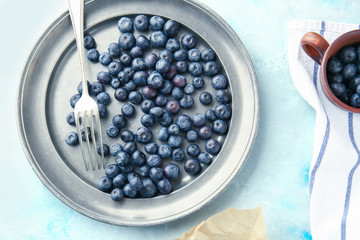 Plate with fresh blueberry on color background
