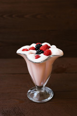 A glass of refreshing raspberry milkshake for breakfast, lunch or dinner with fresh raspberries and brownberries on a brown wooden background in a glass tumbler. Menu for a cafe or restaurant