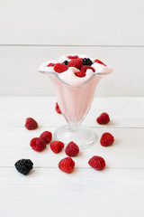 A glass of refreshing raspberry milkshake for breakfast, lunch or dinner with fresh raspberries and ice cream on a white wooden background. Menu for a cafe or restaurant