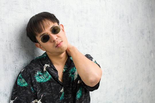 Young chinese man wearing summer outfit suffering neck pain