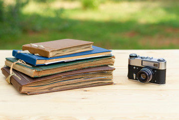 Old photo albums old camera on a light wooden table in the summer garden.