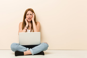 Young ginger woman sitting on her house floor whining and crying disconsolately.