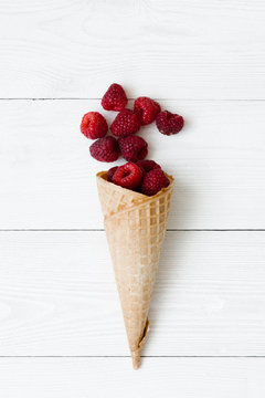 Cascade of fresh raspberries in a waffle cone of ice cream on a white background. Cafe or restaurant menu