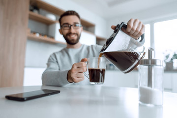 attractive man pours himself a cup of delicious coffee