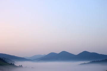 Mountain range with visible silhouettes through the morning colorful fog