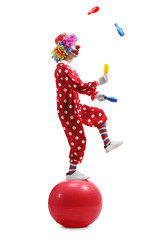 Clown juggling and standing on a ball