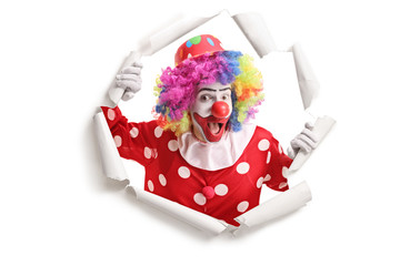 Cheerful clown peeking through a paper hole
