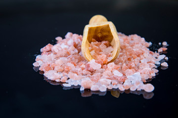 salt on black background with wooden spoon