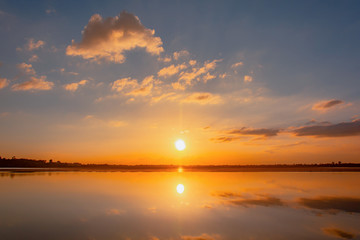 Obraz premium Sunset reflection lagoon. beautiful sunset behind the clouds and blue sky above the over lagoon landscape background. dramatic sky with cloud at sunset