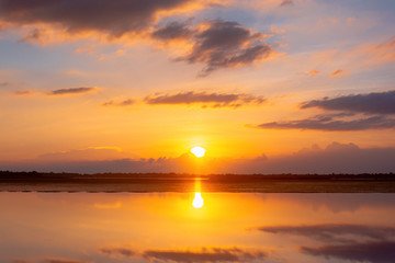 Sunset reflection lagoon. beautiful sunset behind the clouds and blue sky above the over lagoon landscape background. dramatic sky with cloud at sunset