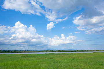 Green field, river and blue sky with light clouds backgrund