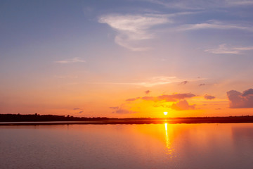 Sunset reflection lagoon. beautiful sunset behind the clouds and blue sky above the over lagoon landscape background. dramatic sky with cloud at sunset