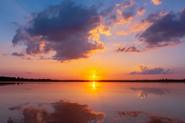 Obraz premium Sunset reflection lagoon. beautiful sunset behind the clouds and blue sky above the over lagoon landscape background. dramatic sky with cloud at sunset