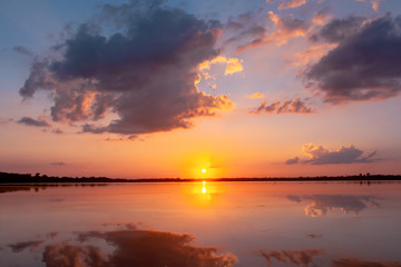 Sunset reflection lagoon. beautiful sunset behind the clouds and blue sky above the over lagoon landscape background. dramatic sky with cloud at sunset