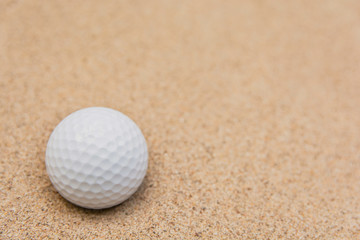 Selective focus of white golf ball on sand bunker
