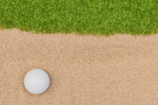 White Golf Ball In Sand Bunker On Golf Court.