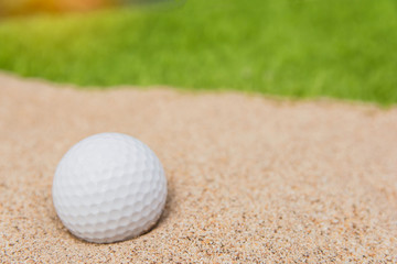White golf ball in sand bunker on golf court.