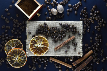 Fresh natural coffee beans scattered on a dark blue background with cinnamon sticks, sliced...