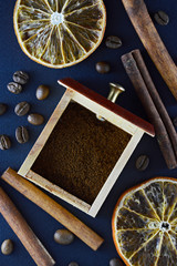 Fresh natural coffee beans scattered on a dark blue background with cinnamon sticks, sliced...