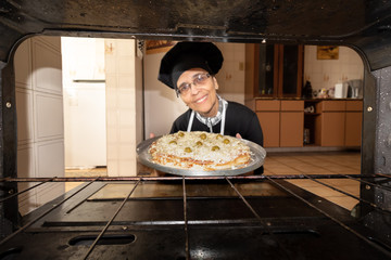 Woman putting a homemade pizza in the Oven