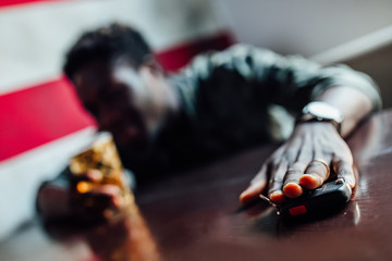 Drink no drive concept. The drunk man sitting in restaurant trying to grab the car key after he drank a lot of whiskey.