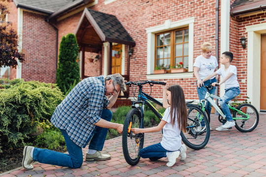 Grandfather near his house with kids repair the bike. Bicycle mechanic in a workshop in the repair process - Powered by Adobe