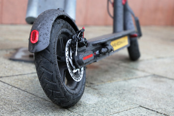 Electric scooter on a parking lot during a rain, water drops on a wheels. City bike rental system,...