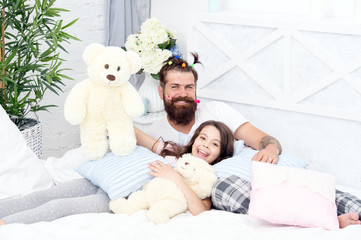 Obraz na płótnie Canvas Dad and girl relaxing in bedroom. Pajamas style. Father bearded man with funny hairstyle ponytails and daughter in pajamas. Having fun pajamas party. Slumber party. Happy fatherhood. Close friends
