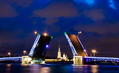 Fototapeta na wymiar A drawbridge of Saint Petersburg at night with a fortress between it and lights reflected in water. Dvortsoviy bridge and the Neva river. White nights. Famous sight in the city of Russia
