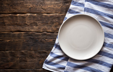 Old cutting board with an empty plate above with a copy space for food on a aged wooden kicthen...