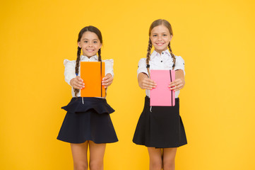 Sharing book love. Happy little girls holding books with colorful covers on yellow background. Cute...