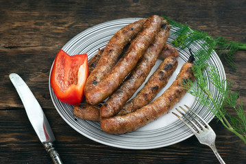 A grilled sausages on a plate on a kitchen table background.