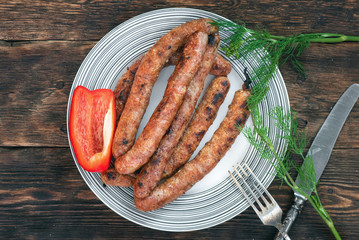 A grilled sausages on a plate on a kitchen table background.