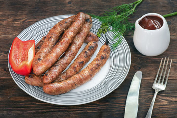A grilled sausages on a plate on a kitchen table background.