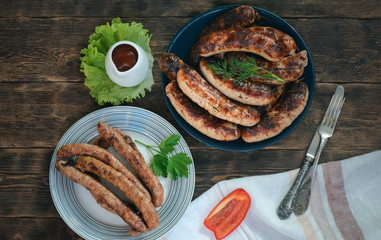 A grilled sausages on a plate on a kitchen table background.