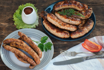 A grilled sausages on a plate on a kitchen table background.