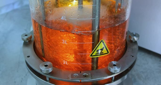 Growing bacteria in a bioreactor. Top view of a glass cylinder with a red one inside, which is mixed. Synthesis of new substances in the laboratory.
