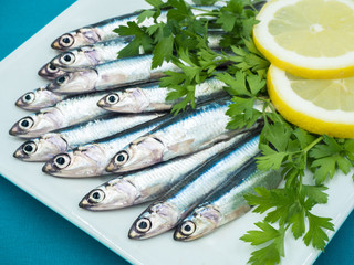 Fresh anchovies in a plate accompanied by lemon and parsley