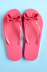 Pink rubber slippers on blue background composition.