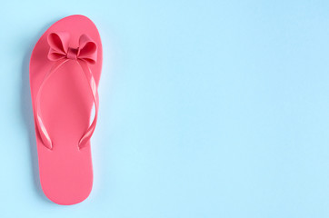 Pink rubber slippers on blue background composition.
