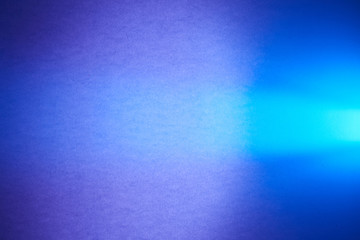 Textured purple and blurred blue background cuts a turquoise ray of light