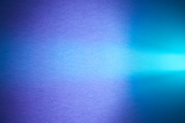 Turquoise ray of light cuts through the purple textural and blurred blue background