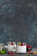 Chia pudding with yogurt and raspberries in a glass on concrete background